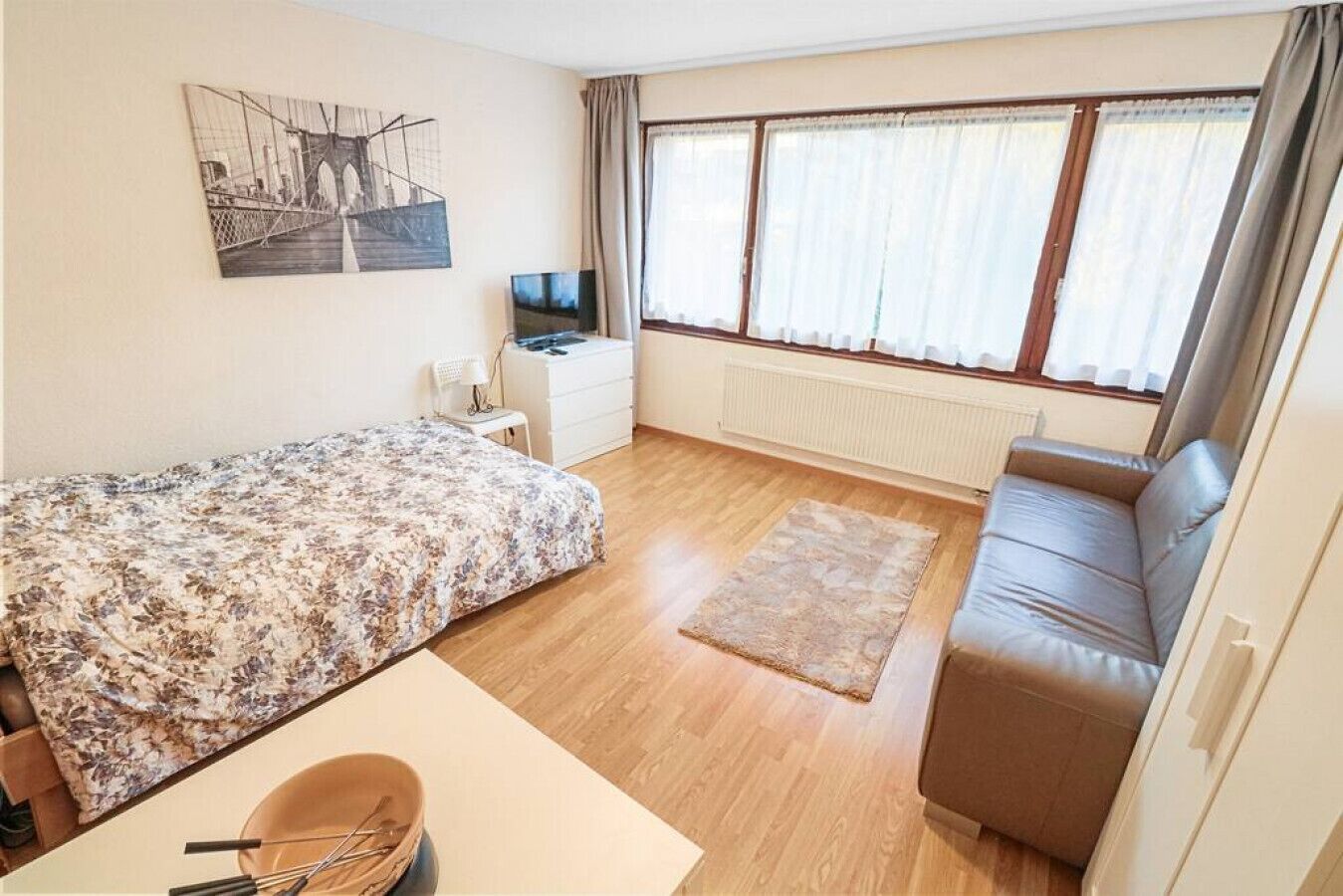 Une chambre à coucher avec un lit, un canapé, un bureau et une télévision.
