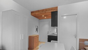 Una cocina compacta con gabinetes blancos, techo de madera y una campana extractora negra.