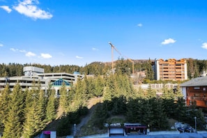 A multi-story building with a modern architectural design, surrounded by dense greenery and a clear blue sky.