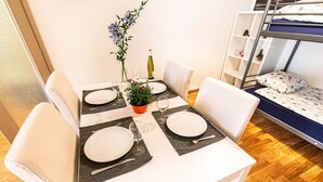 A dining area with a white table set for two, a potted plant, and a bottle of wine. - Clavan 24 - Hiking, mountain walking, quiet area, skiing (Crans-Montana)