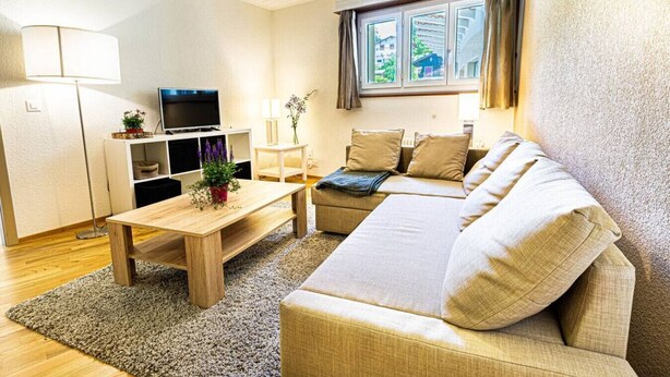 A modern living room with a sofa, a coffee table, a TV, and a window with curtains. - Clavan 24 - Hiking, mountain walking, quiet area, skiing (Crans-Montana)
