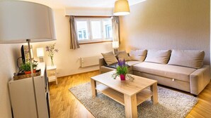 A modern living room with a sofa, a coffee table, a lamp, and a radiator. - Clavan 24 - Hiking, mountain walking, quiet area, skiing (Crans-Montana)