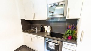 A modern kitchen with white cabinets, a stainless steel oven, a built-in microwave, and a sink. - Clavan 24 - Hiking, mountain walking, quiet area, skiing (Crans-Montana)