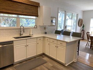 Una cocina moderna con armarios blancos, lavavajillas de acero inoxidable y una isla grande con asientos.