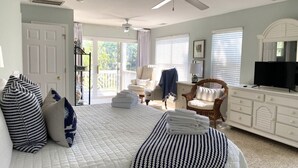 A bedroom with a bed, a chair, a TV, and a balcony.