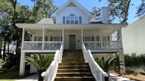 A two-story house with a front porch, a staircase leading to the entrance, and a well-maintained lawn.