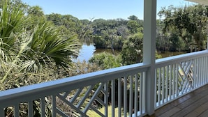 A covered porch with a view of a river and surrounding greenery.