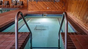 An indoor swimming pool with tiled walls and a wooden floor.