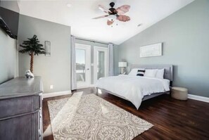A bedroom with a bed, a ceiling fan, a nightstand, and a window.