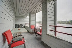 A balcony with a table and chairs, a view of a body of water, and a railing.