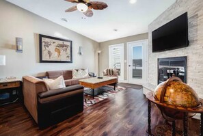 Relax in this inviting living room with a sofa, ottoman, and coffee table, featuring a large window with a view and a fireplace.