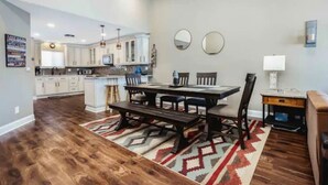 A spacious kitchen with white cabinets, a dining table with chairs, and a rug.