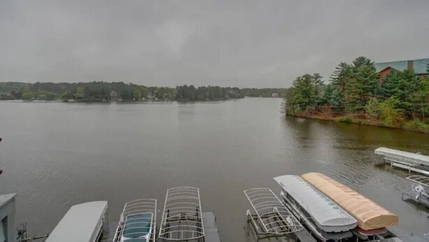 A calm lake with a dock and covered boat storage in the foreground.