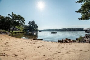 Ein sandiger Strand mit einem ruhigen See, einer Anlegestelle und einem Boot.