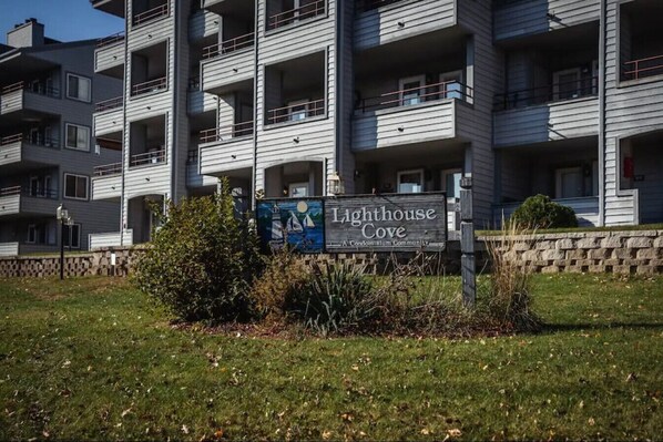 A multi-story residential building with balconies and a sign indicating it is a condominium community named Lighthouse Cove.