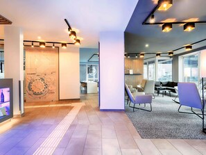 Un espacio de oficina moderno con un mapa grande en la pared, una zona de estar con sillas y una escalera.