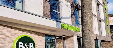 A hotel reception area with a modern design, including a reception desk and a sign indicating the reception.