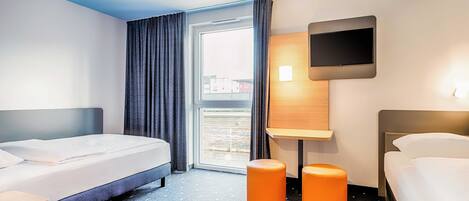 Habitación de hotel con dos camas, televisión y ventana con cortinas.