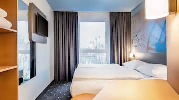 Ein Hotelzimmer mit zwei Betten, einem Fernseher, einem Fenster mit Vorhängen, einem Wandbild mit einer Landkarte und einem kleinen Tisch.