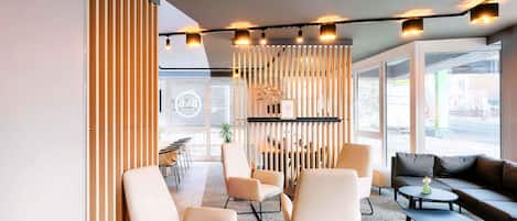 A modern lounge area with seating, a coffee table, and a decorative wall.