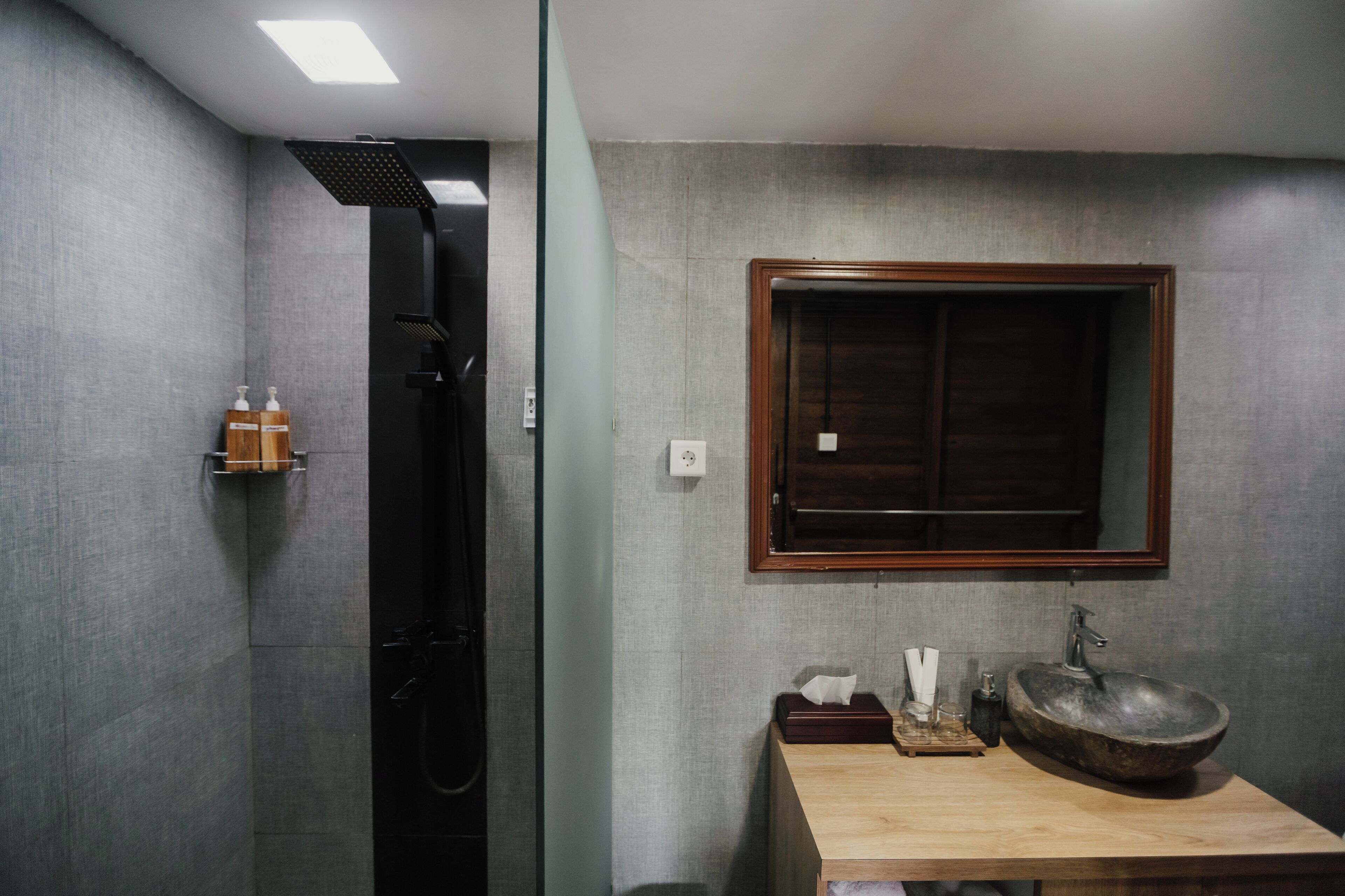 A bathroom with a wooden vanity, a large mirror, and a built-in shower.