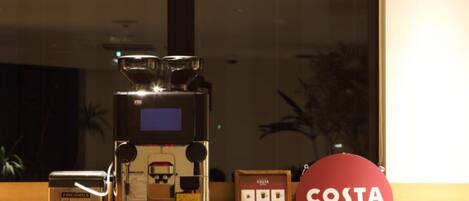 A coffee machine, a grinder, and a Costa Coffee sign on a counter.