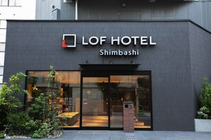 The exterior of Lof Hotel Shimbashi with a modern facade, large glass entrance, and a small outdoor seating area. - LOF HOTEL Shimbashi (Tokyo)