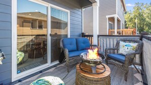 An outdoor patio with a fire pit, wicker furniture, and a sliding glass door leading to a covered area. - Impeccable 4 BR Home in Heart of Port Orchard (Port Orchard)