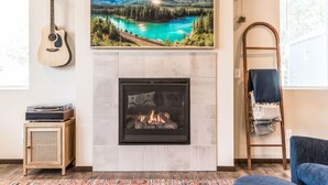 A living room with a fireplace, a mounted guitar, a framed landscape painting, and a ladder against the wall. - Impeccable 4 BR Home in Heart of Port Orchard (Port Orchard)