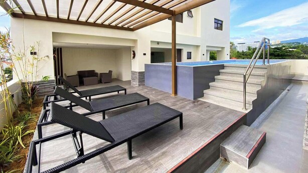 A modern outdoor patio with black lounge chairs and a covered seating area. - Enjoy the luxury and comfort of living (Cebu)