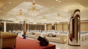 A spacious hotel lobby with multiple seating areas, elegant chandeliers, and a modern design.