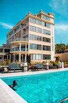 Un hotel con zona de piscina, varios balcones y un cielo azul despejado.