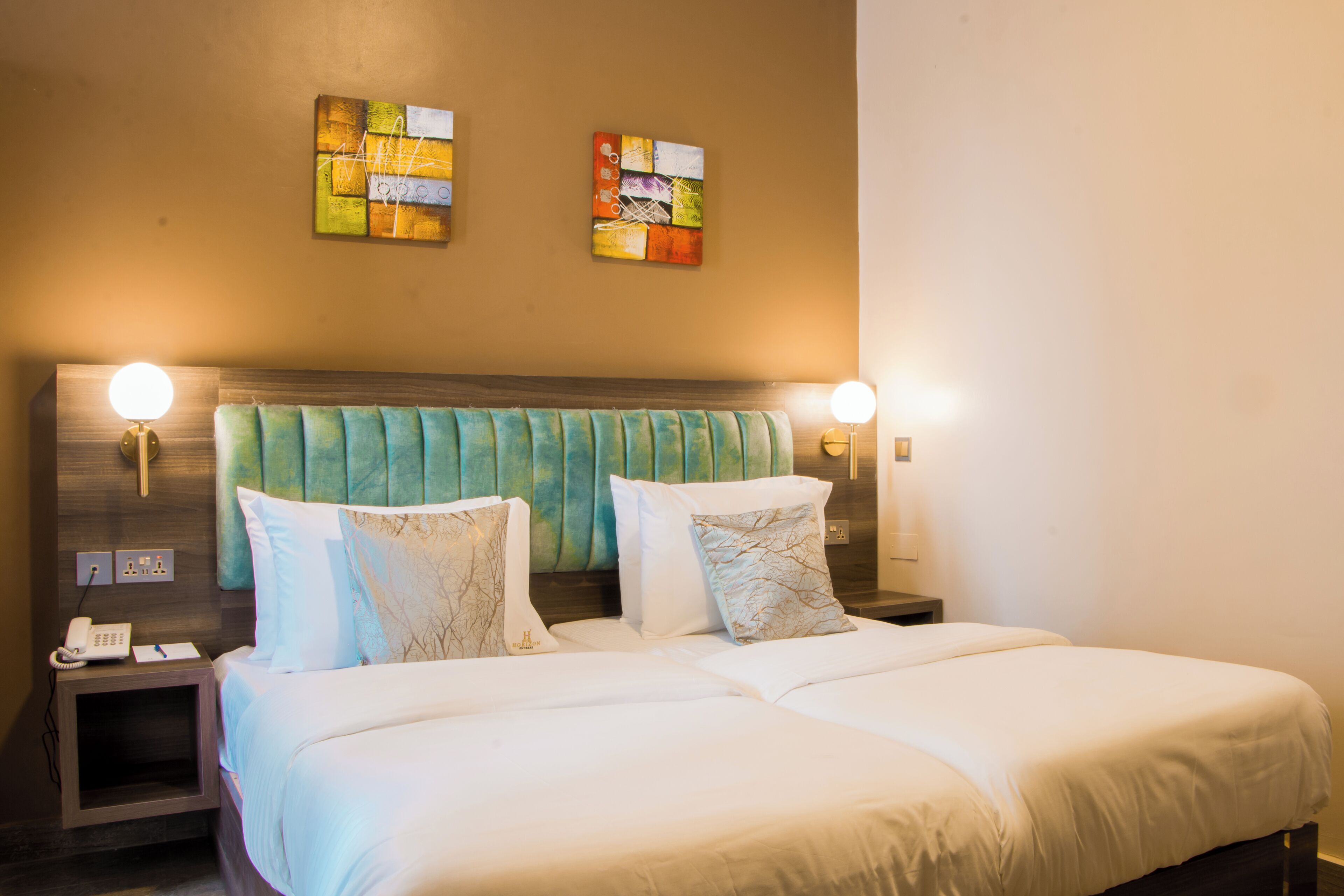 A hotel room with a large bed, two bedside tables, a telephone, and wall-mounted lamps.