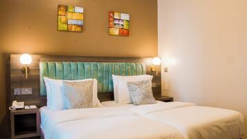 A hotel room with a large bed, two bedside tables, a telephone, and wall-mounted lamps.