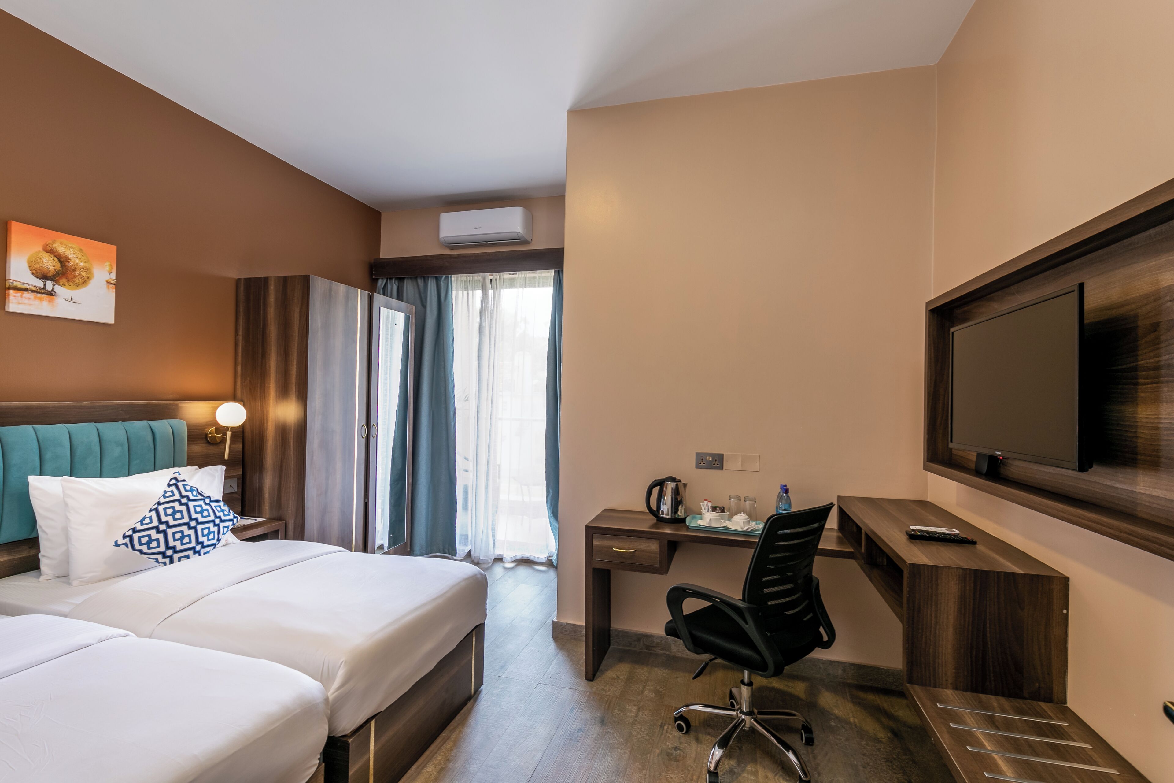 Une chambre d’hôtel avec un lit, un bureau, une chaise, une télévision et un tableau au mur.