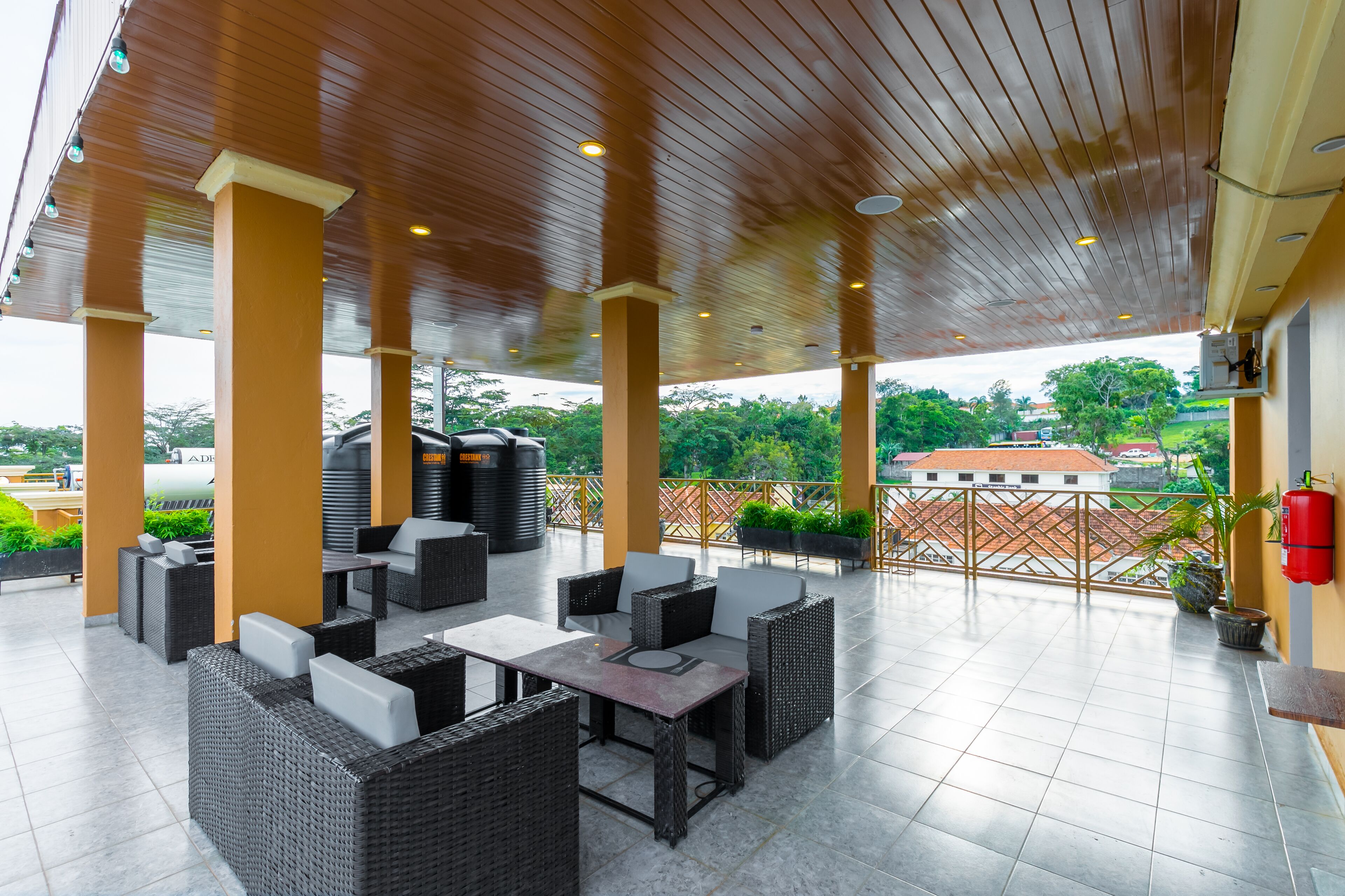 Een terras buiten met rieten meubilair, een betegelde vloer en uitzicht op het omliggende landschap.