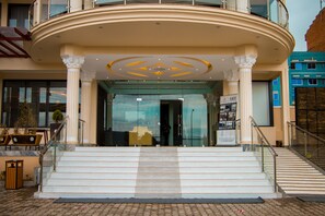 A grand entrance with a curved balcony, a staircase leading up to the entrance, and a clear view of the interior through the glass doors. - Hotel Horizon Entebbe (Entebbe)