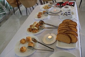 A breakfast buffet with various pastries, bread, and a lit candle on a table. - Hotel Horizon Entebbe (Entebbe)
