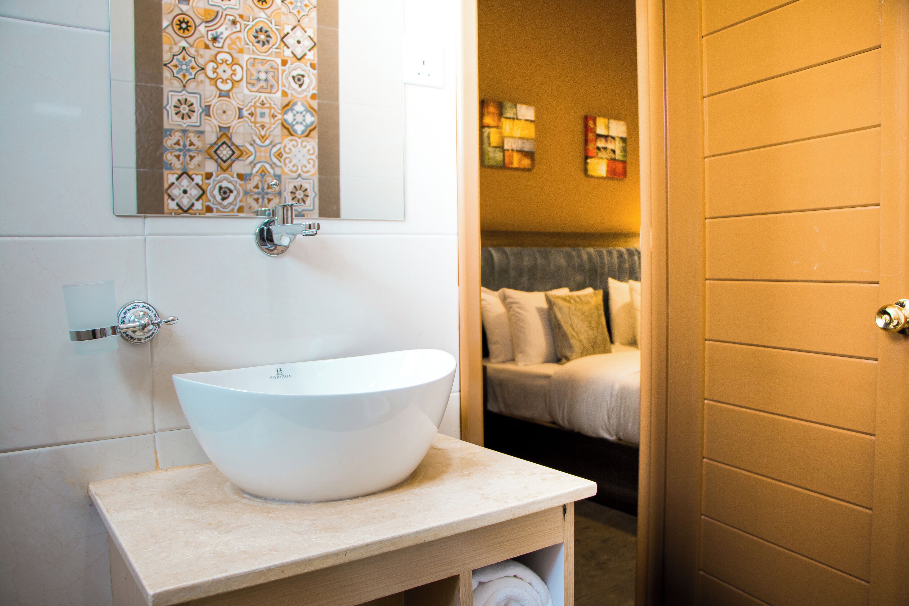 A bathroom with a white sink, a mirror, and a patterned tile backsplash.
