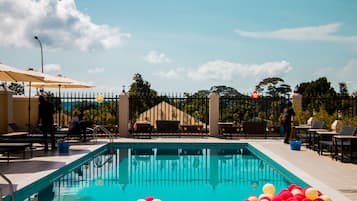 Una piscina al aire libre, sombrillas, sillones reclinables de piscina