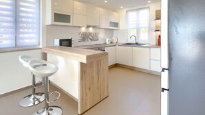 Eine moderne Küche mit einer zentralen Kochinsel, weißen Schränken und einem Edelstahl-Kühlschrank.