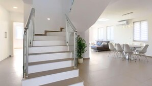 Ein modernes Interieur mit Treppe, Essbereich und Wohnbereich.