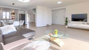Ein modernes Wohnzimmer mit einem Glastisch, einer Couch und einem Fernseher.