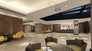 En rummelig lobby med moderne møbler, højt til loftet og ovenlys.