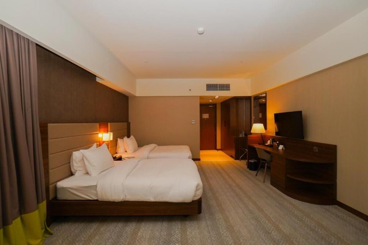 Une chambre d’hôtel équipée d’un lit, de lampes de chevet, d’un bureau, d’une chaise et d’un téléviseur.