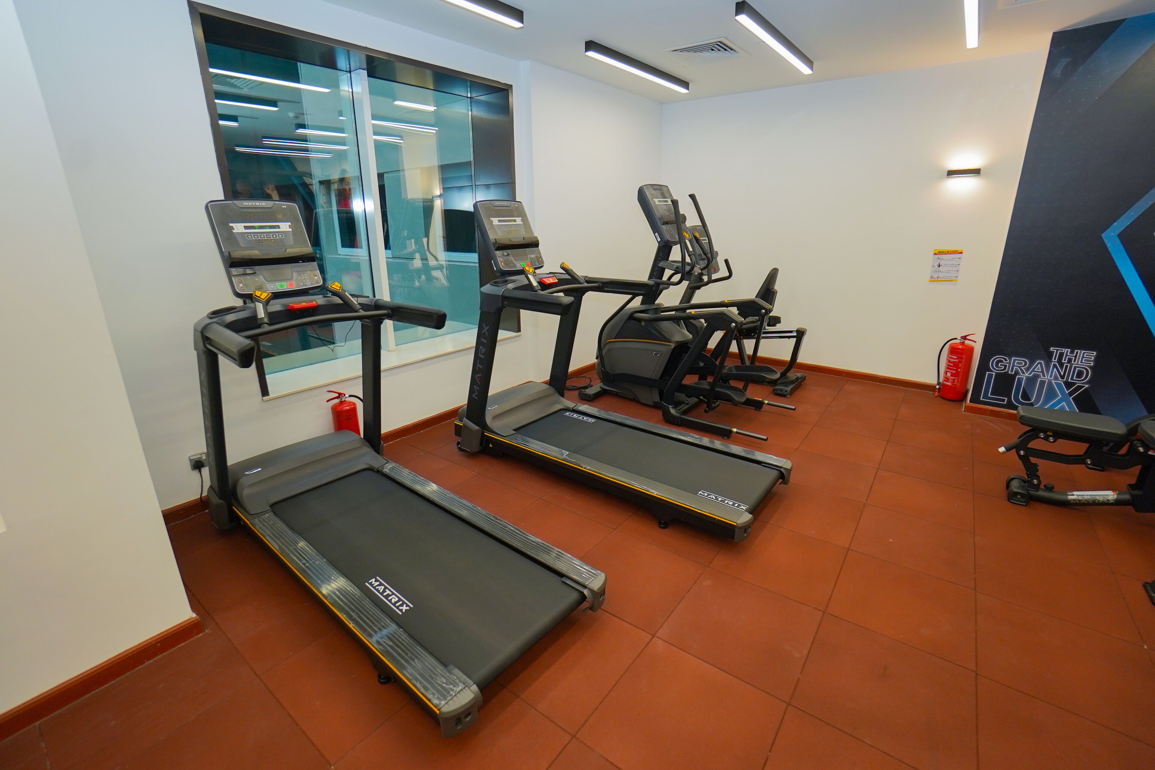 A gym with treadmills, exercise bikes, and a fire extinguisher.