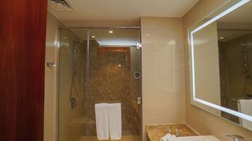 Une salle de bain moderne avec une douche à parois de verre, un lavabo en marbre et un grand miroir.