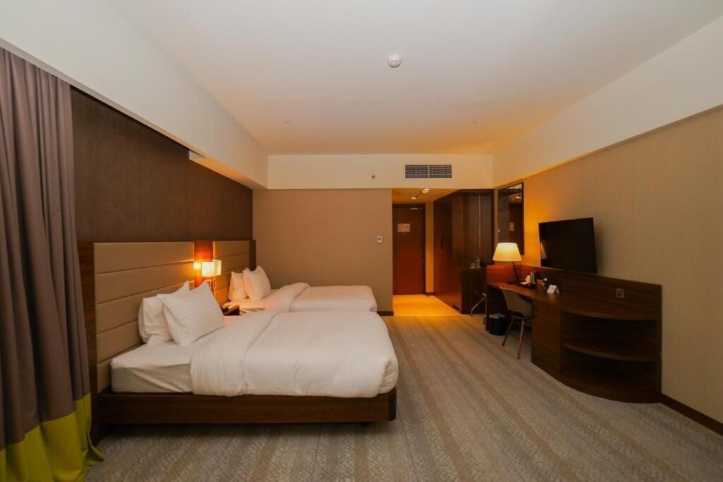 Ein Hotelzimmer mit Bett, Nachttischlampen, Schreibtisch, Stuhl und Fernseher.
