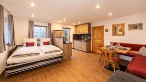 Une chambre d’hôtel de taille réduite, comprenant un lit, une kitchenette et un coin repas.