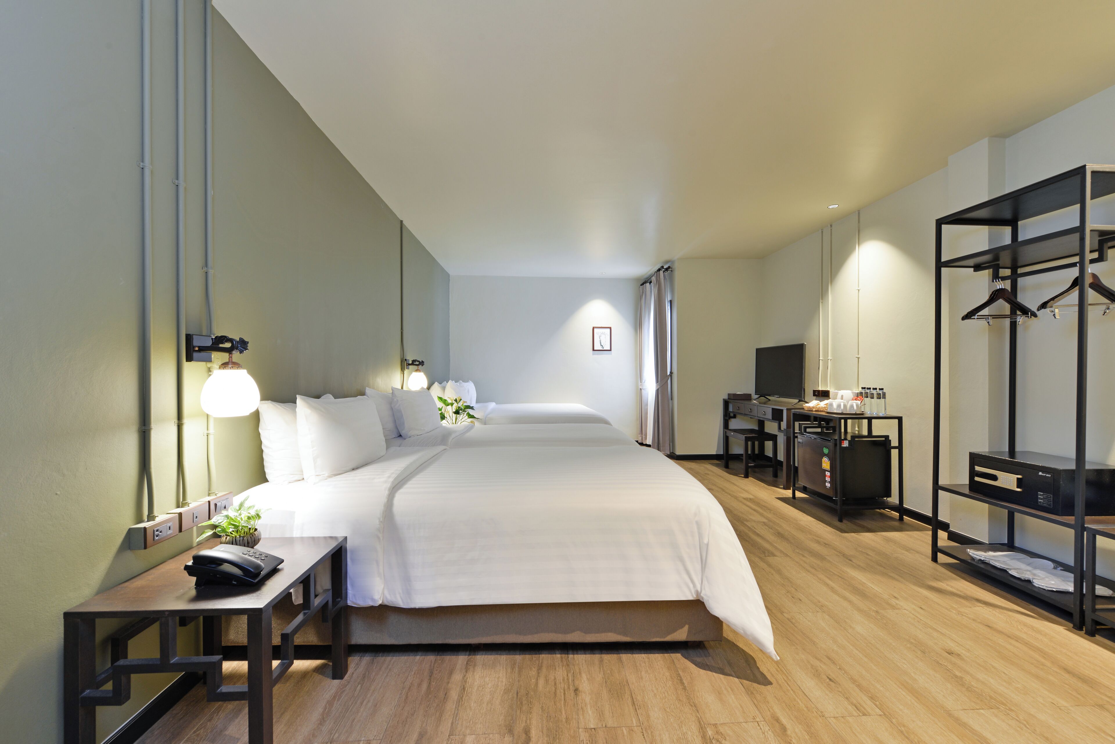 A modern hotel room with a large bed, bedside tables, a desk, and a wardrobe.